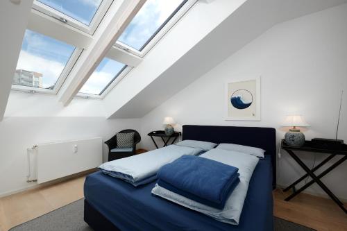 Un dormitorio con una cama azul y algunas ventanas en Dock19, en Heikendorf