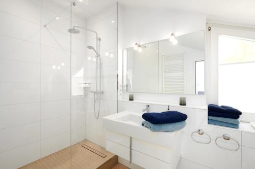 Baño blanco con lavabo y espejo en Dock19, en Heikendorf