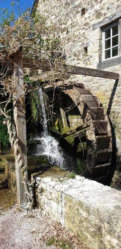 AignervilleNormandieheritage14 Moulin de la Bretonnière - OMAHA BEACH的建筑物前有一座石桥，桥下是瀑布。