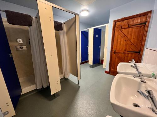 ein Badezimmer mit einem Waschbecken und einer Holztür in der Unterkunft Lands End Hostel and B&B in Sennen