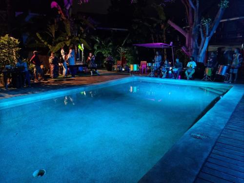 a swimming pool at night with people standing around it at Hotel Esplanada in Dili