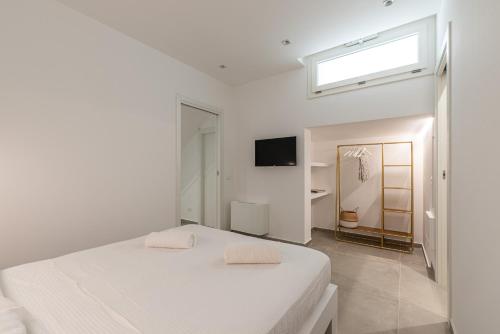 ein weißes Schlafzimmer mit einem Bett und einem Fenster in der Unterkunft Villa alla Baia dei Sette Emiri by Wonderful Italy in Cefalú