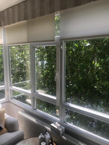 3 ventanas en una sala de estar con vistas a los árboles en Gayrettepe Beşiktaş da büyük daire, en Estambul