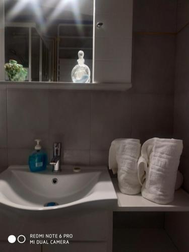 ein Badezimmer mit einem Waschbecken, einem Spiegel und Handtüchern in der Unterkunft Muses apartments in Eretria
