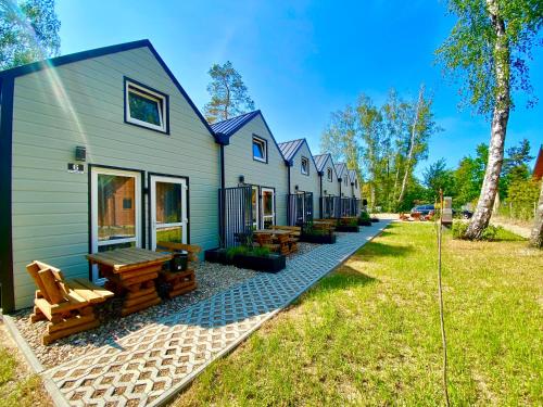 a row of houses with benches on the grass at Domy nad morzem- Family Resort - Chata Pirata 2 in Dziwnów