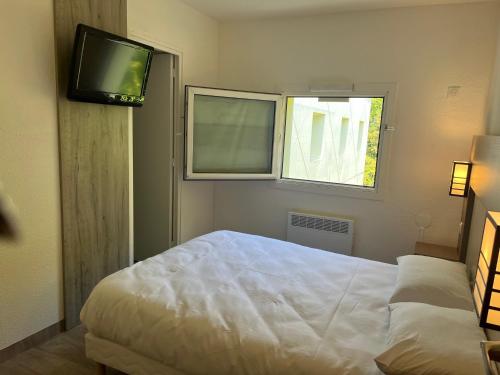 1 dormitorio con 1 cama y TV en la pared en Class'Eco Chambly, en Chambly