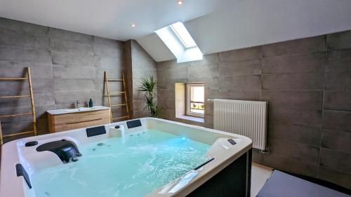 een badkamer met een groot bad en een wastafel bij Le Clos des écureuils - chambres d'hôtes in Sainte-Marie-la-Blanche