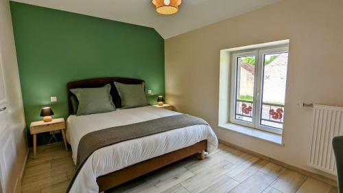 Dormitorio verde con cama y ventana en Le Clos des écureuils - chambres d'hôtes en Sainte-Marie-la-Blanche