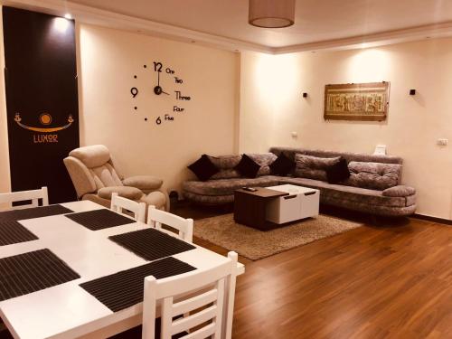a living room with a table and a clock on the wall at Sphinx Luxor Apartment in Luxor