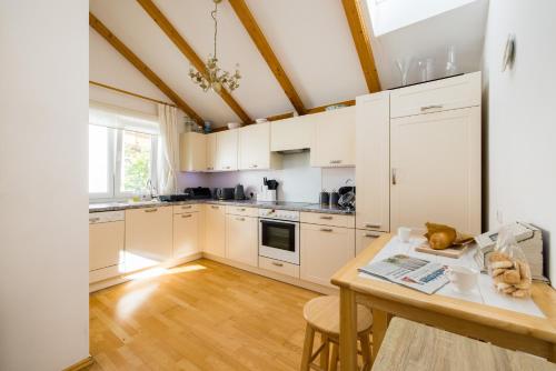 uma cozinha com armários brancos e uma mesa de madeira em Pfamhaus Penthouse em St. Wolfgang