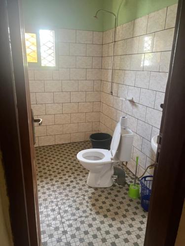 a bathroom with a toilet and a tiled floor at A&G Guest House Kumba in Kumba