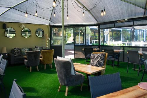 un restaurante con mesas, sillas y alfombra verde en Silver Forest Boutique Hotel and Spa en Somerset West