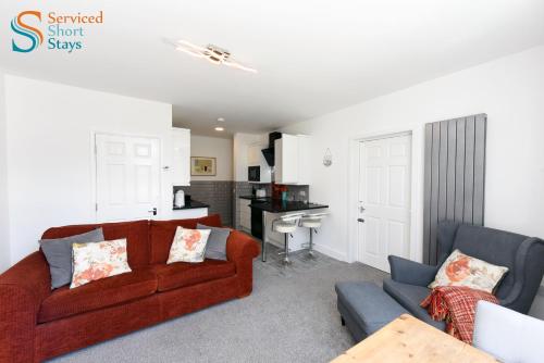 a living room with a red couch and a desk at Two bedroom ground floor apartment near the beach in Margate