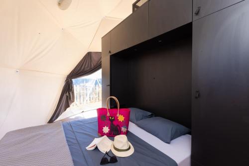 een bed in een tent met een roze zak erop bij Les Dômes des Gorges in Ruoms
