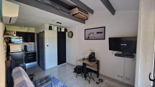 un salon avec un canapé, une table et une télévision dans l'établissement Maisonnette Port Leucate vue sur mer, à Port-Leucate