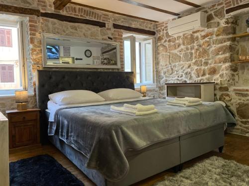 sypialnia z dużym łóżkiem i kamienną ścianą w obiekcie Tequila Apartments w mieście Zadar