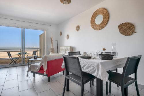 une salle à manger avec une table et des chaises et un balcon dans l'établissement Face Mer - Bel appartement pour 4, à Saint-Brévin-les-Pins