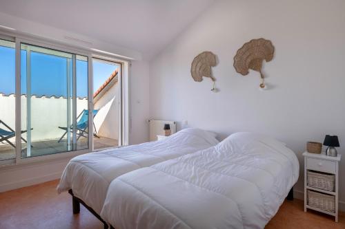 a white bedroom with a bed and a large window at Face Mer - Bel appartement pour 4 in Saint-Brevin-les-Pins