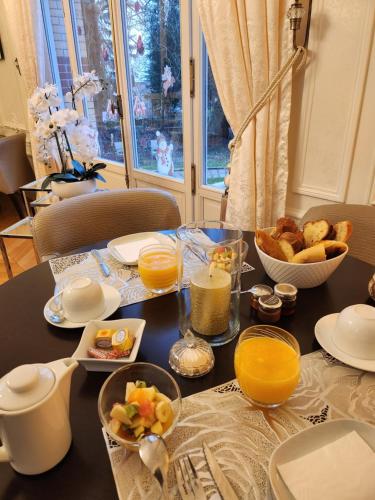 a table with breakfast foods and orange juice on it at Château de La Feuilleraie in Saint-Leu-la-Forêt