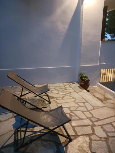 Cette chambre dispose d'une chaise et d'un sol en pierre. dans l'établissement Theros & Trygos Boutique Houses - ATH Airport, à Artemi