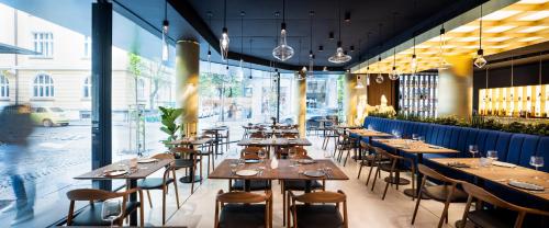 un restaurante con mesas y sillas de madera y ventanas en Juno Hotel Sofia, a Member of Design Hotels en Sofía