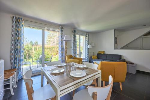 un salon avec une table, des chaises et un canapé dans l'établissement Les Roséales - Maison proche plage pour 6 voyageurs, à Courseulles-sur-Mer