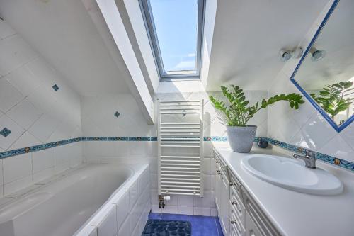 a bathroom with a tub and a sink and a window at Les Roséales - Maison proche plage pour 6 voyageurs in Courseulles-sur-Mer