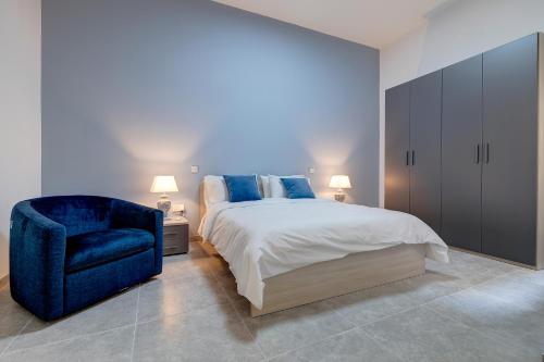 een slaapkamer met een bed en een blauwe stoel bij Modern 3BR Apartment in Sliema's Desirable Locale in Sliema