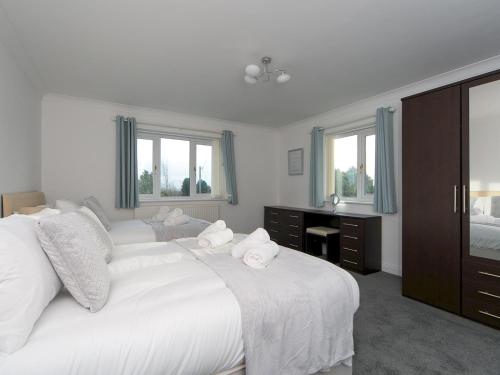 a white bedroom with a large bed and a desk at Pass the Keys Cysgod Eryri Spacious House near Anglesey Coast in Brynteg