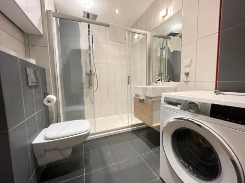 uma casa de banho com uma máquina de lavar roupa e um lavatório em Apartament Park Zakrzowek em Cracóvia
