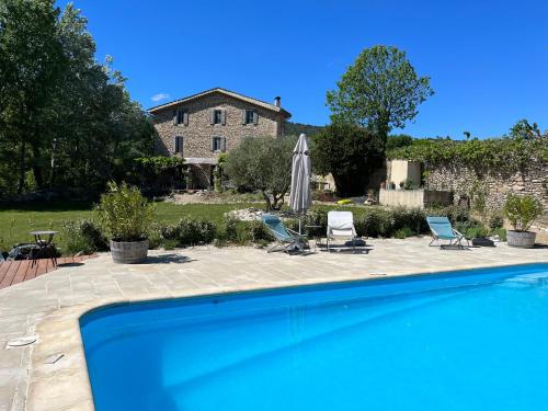 een zwembad met twee stoelen en een huis bij Mas Lou Parpaioun in Crestet