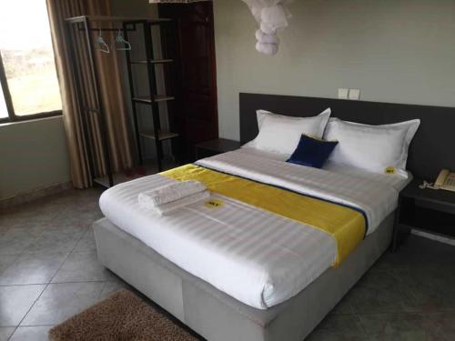a bedroom with a large bed with yellow and white pillows at Sky Beach Hotel in Wakiso