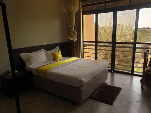 a bedroom with a bed with yellow and white pillows at Sky Beach Hotel in Wakiso