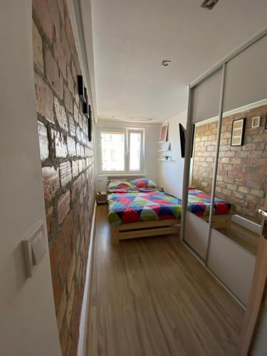 a bedroom with two beds and a brick wall at Dwa pokoje w centrum - darmowy parking in Świnoujście