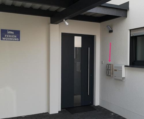a black door on a white wall with a pink arrow at -Neubau- 30qm Dach-Apartment in Fulda