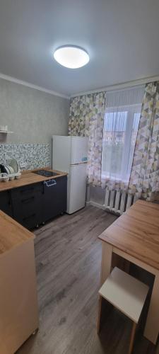 an empty kitchen with a white refrigerator and tables at 1 комнатная квартира со всеми удобствами in Balqash