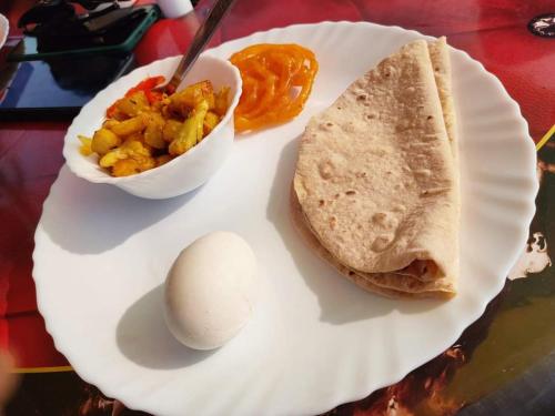 une assiette avec un œuf, un sandwich et un bol de fruits dans l'établissement Chamtaburu Eco Resort, à Bāghmundi
