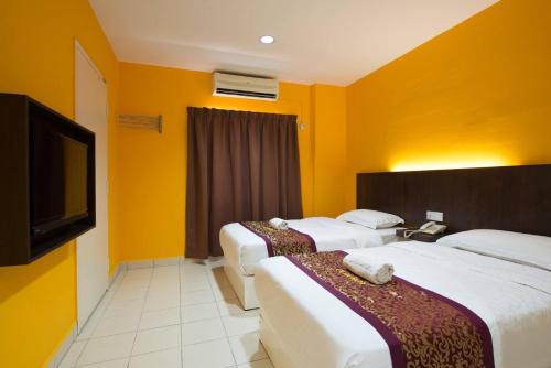 マラッカにあるSC Hotel Melakaのベッド3台、薄型テレビが備わるホテルルームです。