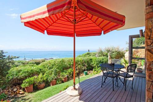 een patio met een tafel en stoelen onder een parasol bij Vitamin-Sea in Kaapstad