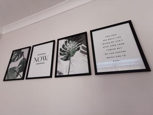 a group of framed pictures on a wall at Apartment by the Beach in Swansea