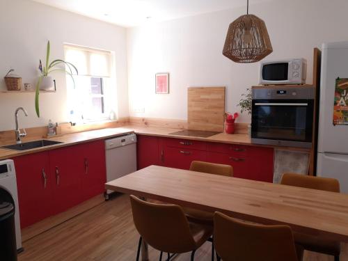 a kitchen with red cabinets and a wooden table at Maison Entière Hameau Monastir del Camp in Passa