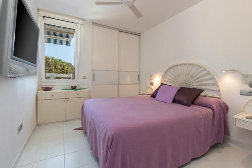 een witte slaapkamer met een paars bed en een raam bij Les Magnolies in Platja  d'Aro