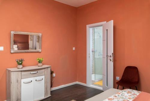 Schlafzimmer mit orangefarbenen Wänden, einem Spiegel und einem Bett in der Unterkunft Spacious Luxury 3BR Apartment with Terrace & Open Views - Zurrieq, close to sea in Żurrieq