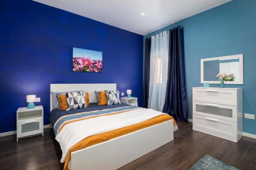 Spacious Luxury 3BR Apartment with Terrace & Open Views - Zurrieq, close to sea في Żurrieq: غرفة نوم زرقاء مع سرير وجدران زرقاء