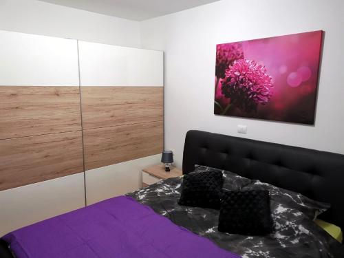 烏馬格的住宿－Apartman Adamović，一间卧室配有紫色的床,墙上挂着一幅大画