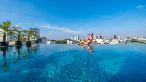 een vrouw staat aan de rand van een zwembad bij The Lapis Hotel in Hanoi