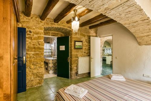 a bedroom with a bed in a room with stone walls at La Masía Grande de Can Gat Vell in Llampaies