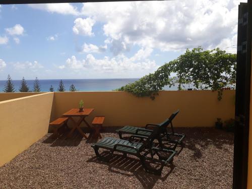 um pátio com uma mesa e duas cadeiras e o oceano em Bela Vista Capazi em Porto Santo