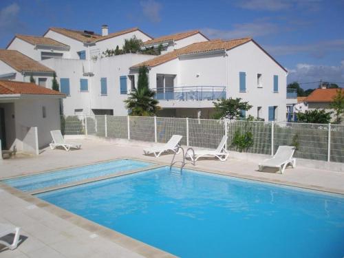 une piscine avec des chaises et une maison dans l'établissement Maison 60m² avec terrasse, piscine, parking privé, à 10 min de la plage - Animaux acceptés - FR-1-494-14, à Vaux-sur-Mer