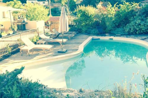 - une piscine avec un parasol et des chaises dans la cour dans l'établissement Villa Roquefortoise avec piscine, à Roquefort-les-Pins